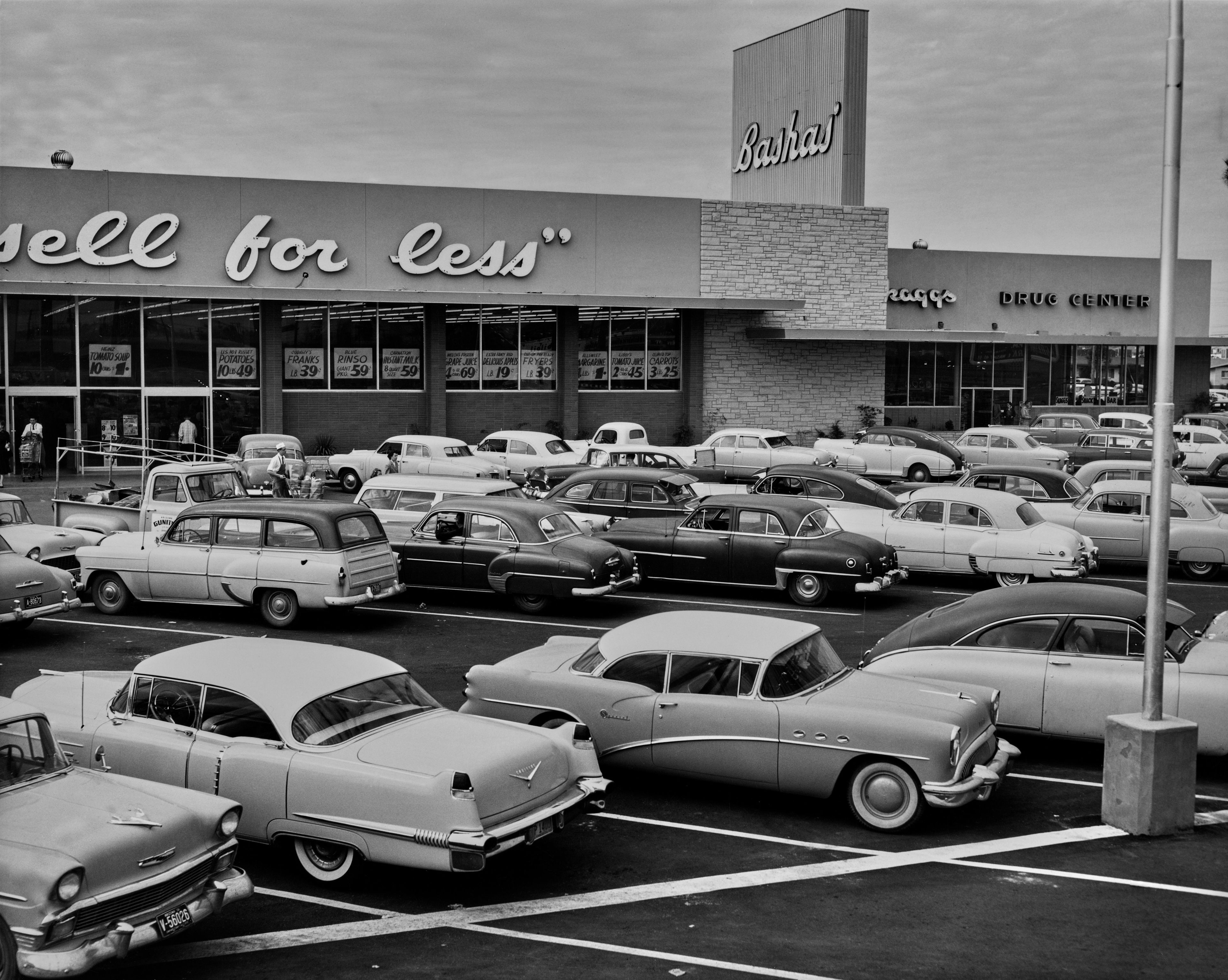 Vintage cars parked outside a mid-20th century department store with "Barnhl" signage visible