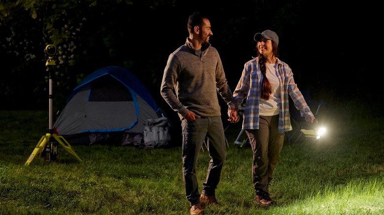 Couple walking around a campsite at night with a Ryobi 360 light.