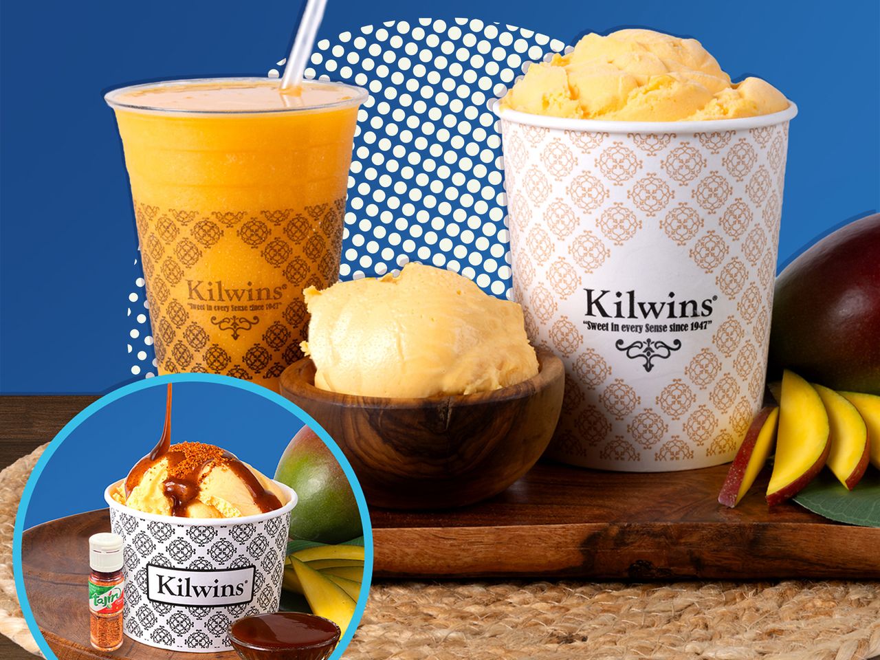 Cups of Kilwins Mango Sorbetto on a wooden surface with mangoes over a blue background