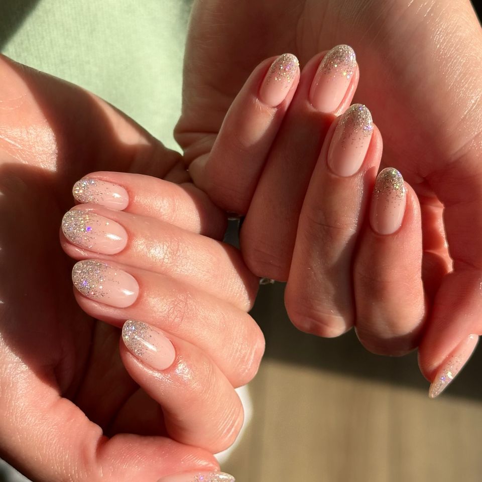 Hands with manicured nails featuring a glittery design