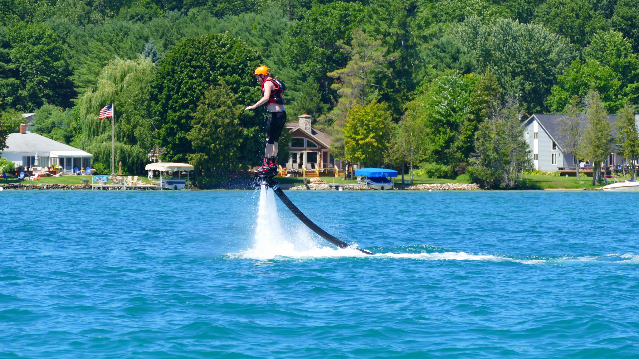 A person flyboarding on Torch Lake, Michigan, near the shoreline.
