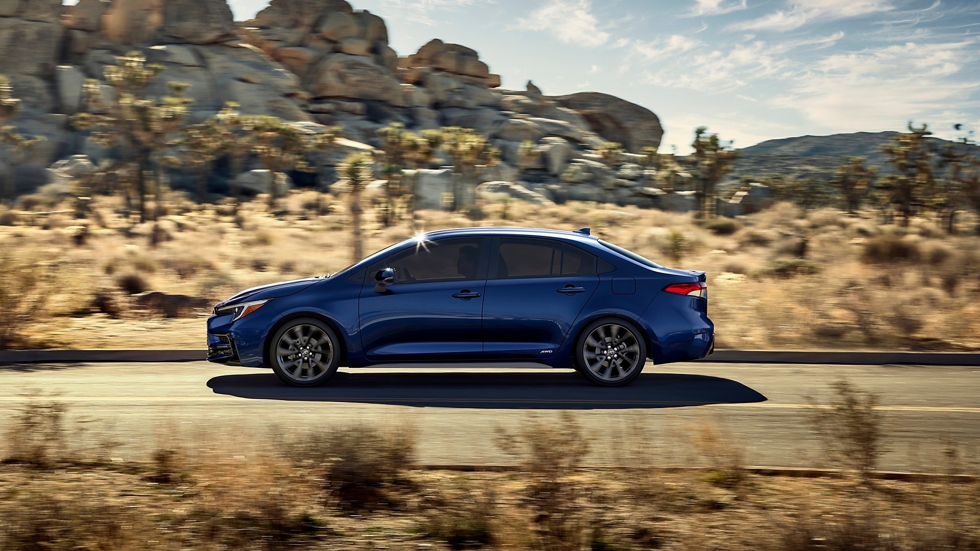 Discover a Toyota Corolla Hybrid (2025 model) being driven on a desert road for promotional photo