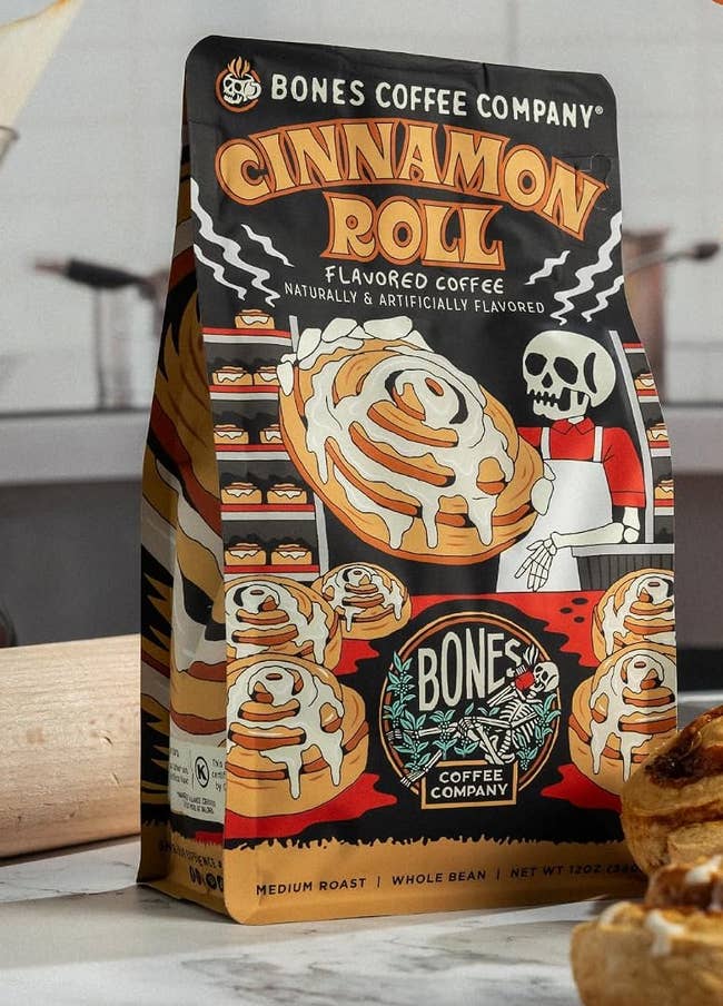 Bones Coffee Company Cinnamon Roll flavored coffee bag with a graphic of cinnamon rolls and a skeleton chef. Medium roast, whole bean, 12 oz