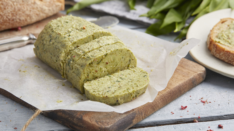 light green garlic compound butter roll on board with bread