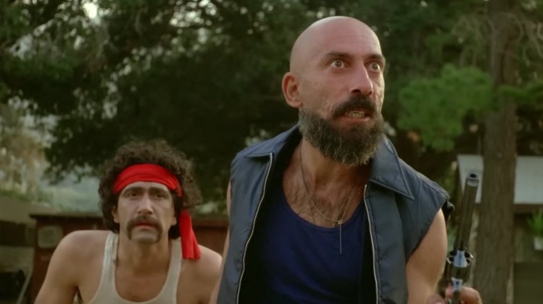Cutter and a henchman racing toward the camera, guns drawn, in The Aftermath