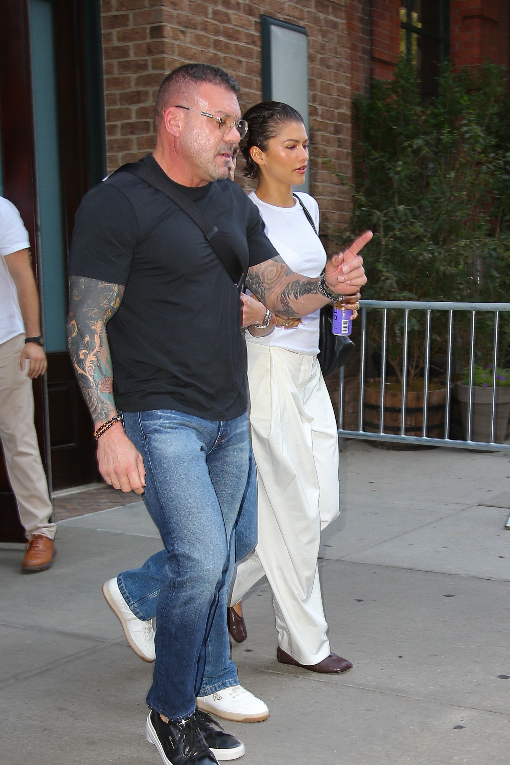 Zendaya wears a white T-shirt and linen pants and has slicked back short hair while holding hands with Tom Holland Ulices Ramales / BACKGRID