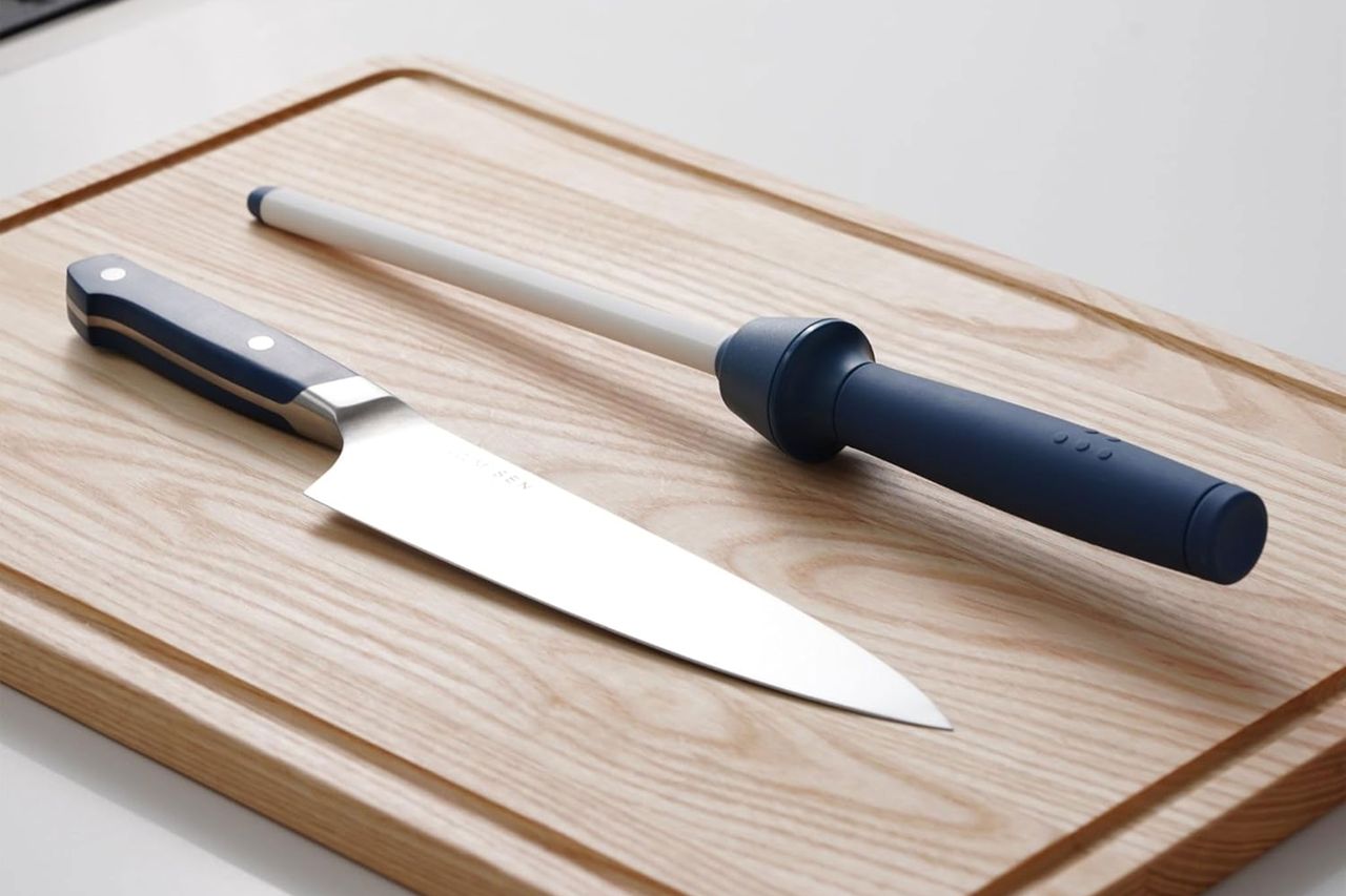 A kitchen knife and a honing steel on a wooden cutting board