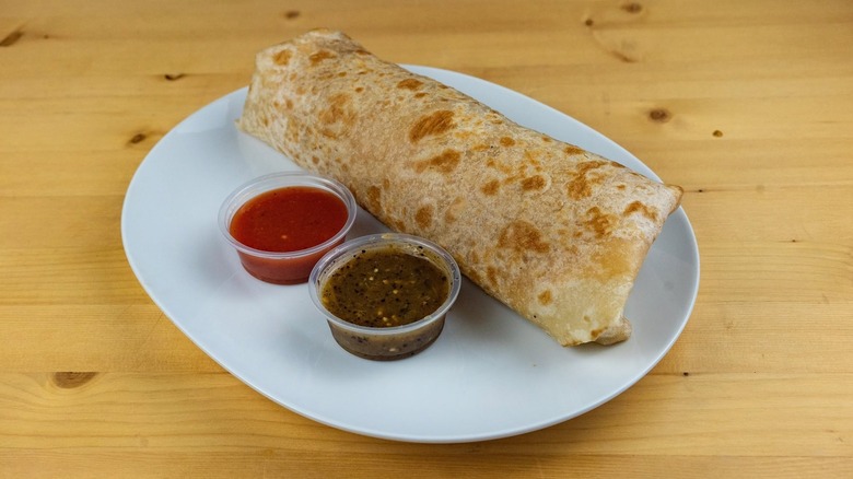Burrito on a plate with sauce on a table