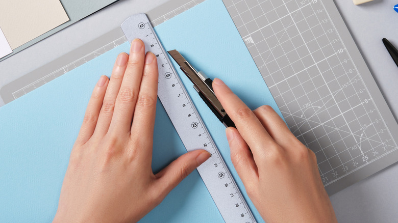 Close-up of a woman using a craft knife to cut paper