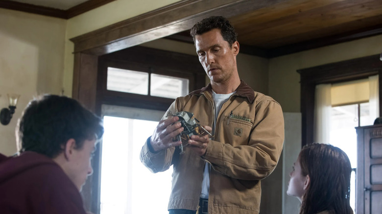 Coop looking at a piece of machinery in front of his kids in Interstellar