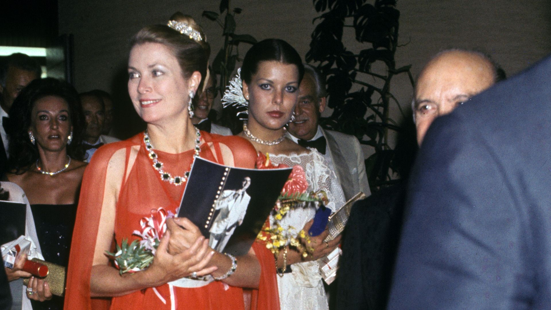 Grace Kelly arrives at the 1976 Monaco Red Cross Ball in a flowing red chiffon gown with a dramatic cape.