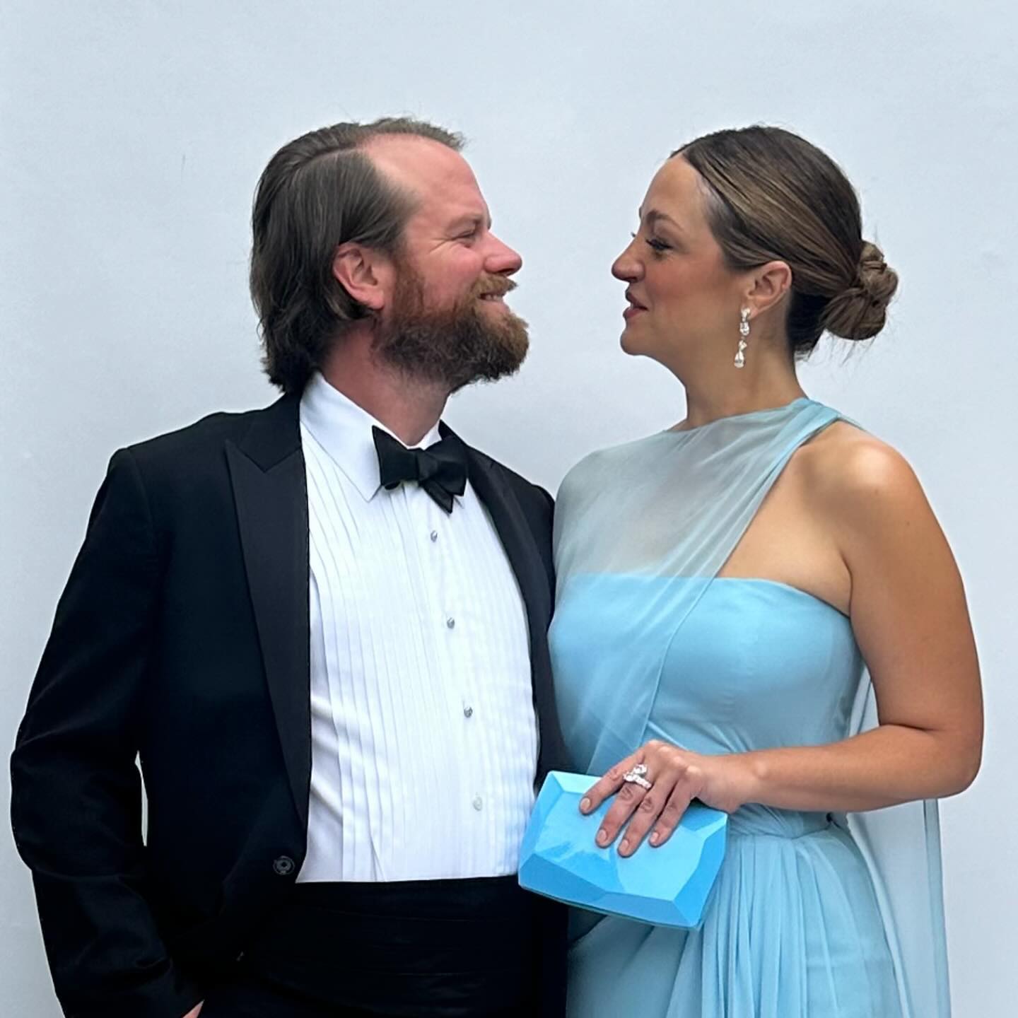 A man in a tuxedo and a woman in a blue gown looking at each other.