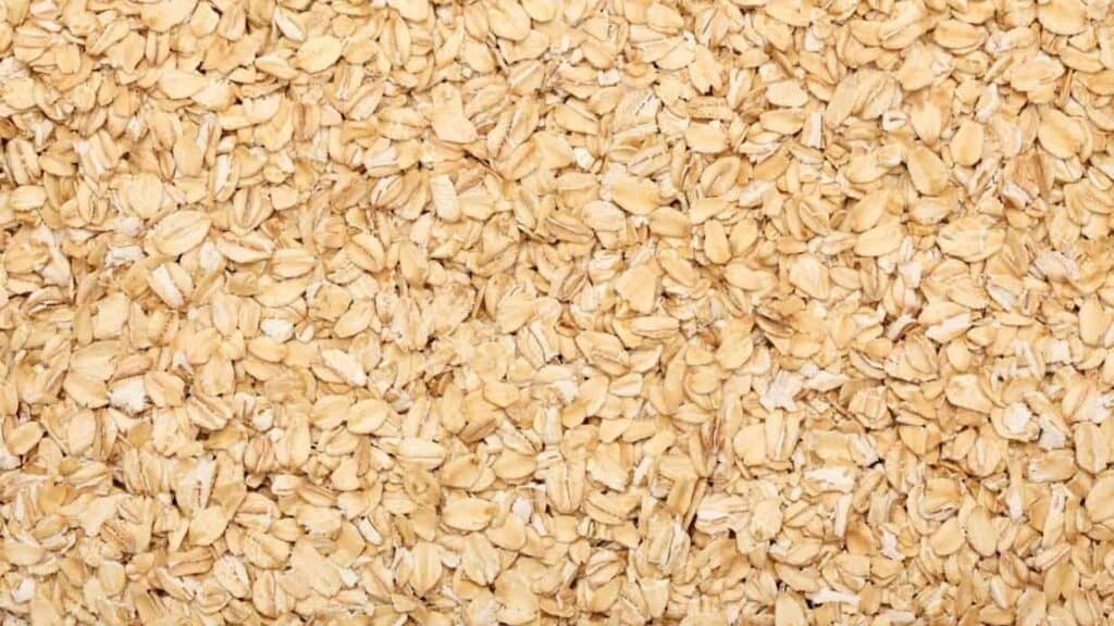 A close-up view of a large amount of rolled oats spread evenly across the entire image.