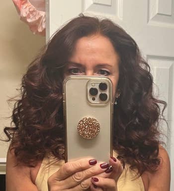 Person with curly hair taking a selfie in a mirror