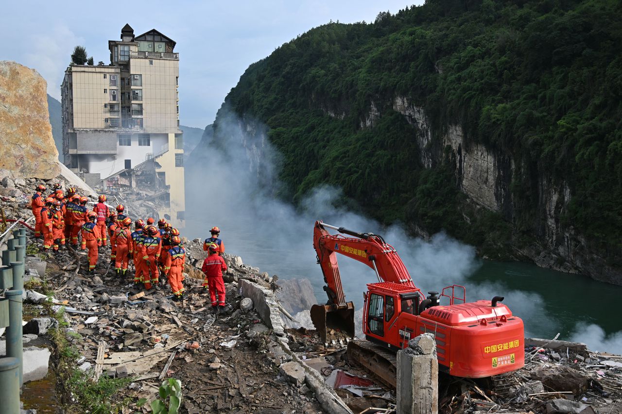 Rescue workers search for survivors at the site of a landslide in Hanjia Street along the Wujiang River