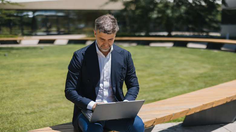 Businessman using laptop with neutral facial expression