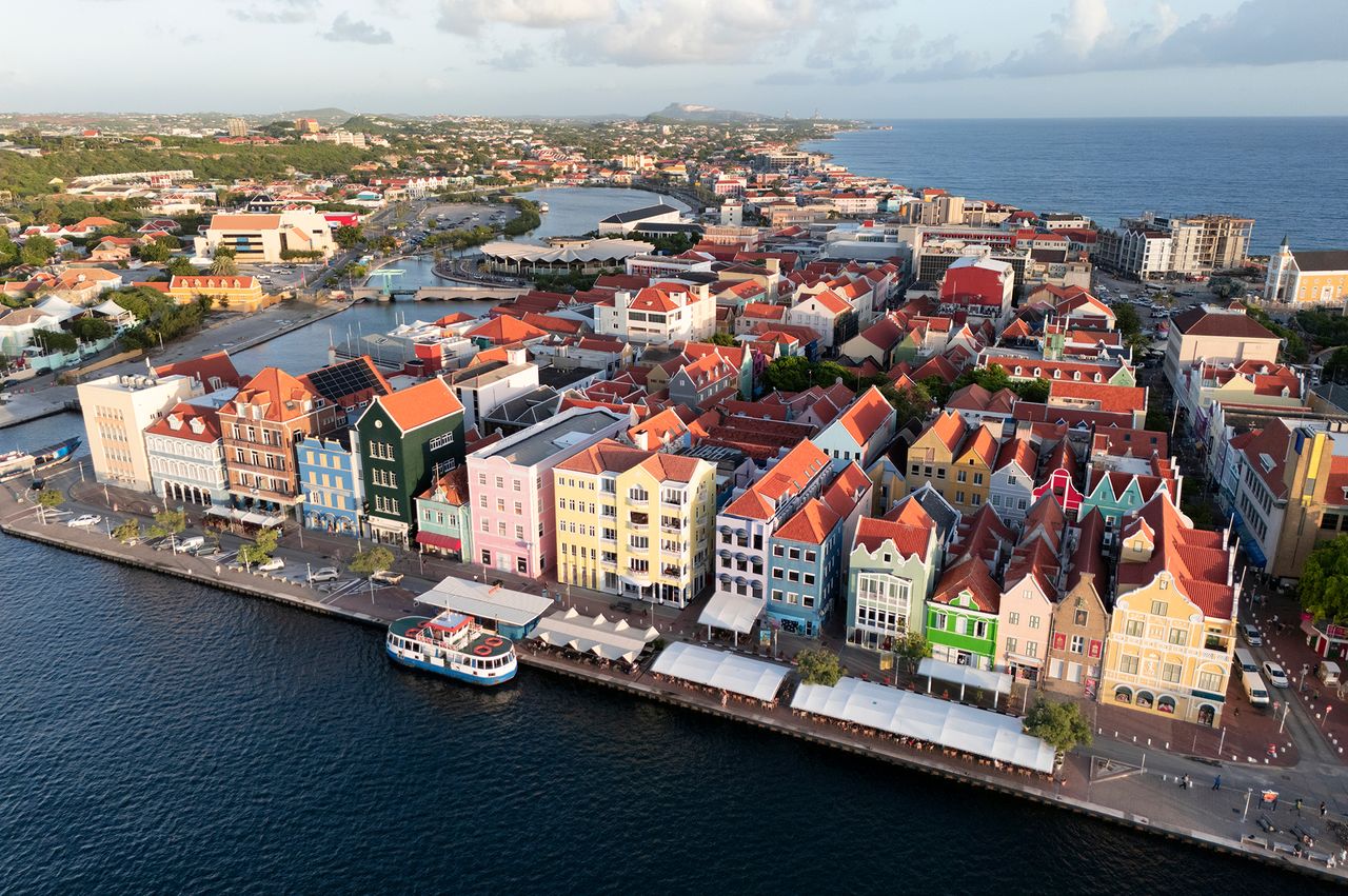 Aerial view of a colorful waterfront cityscape along a coast with rows of buildings and a docked boat