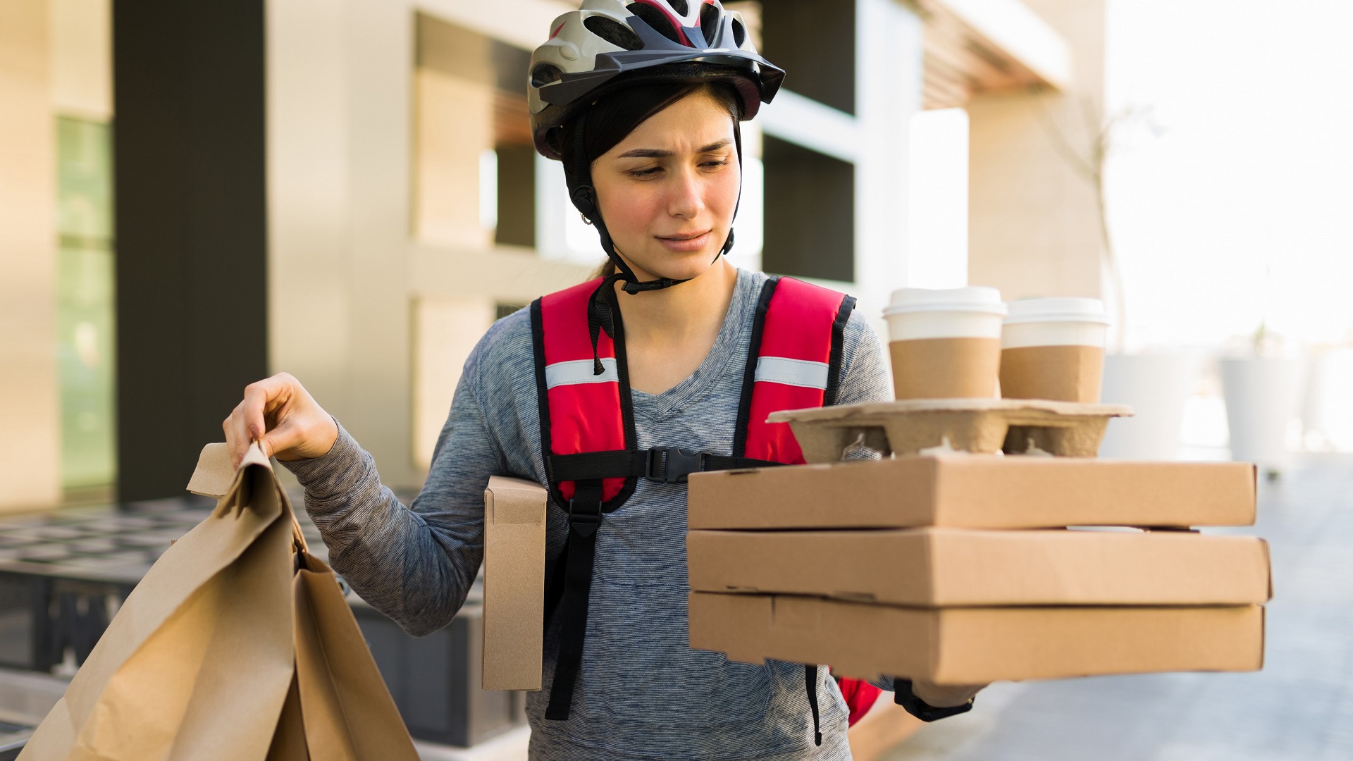 Discover a tired delivery person holding several packages of food, ready for delivery to a customer