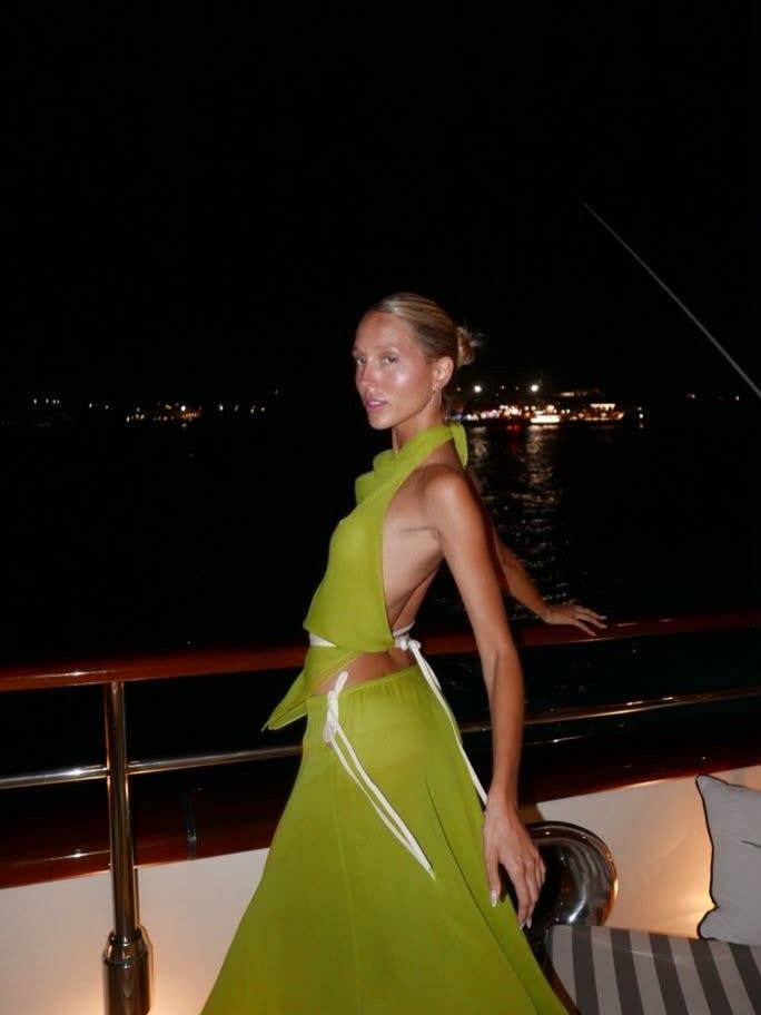 Olympia of Greece and Denmark stands on a yacht at night in a green dress.