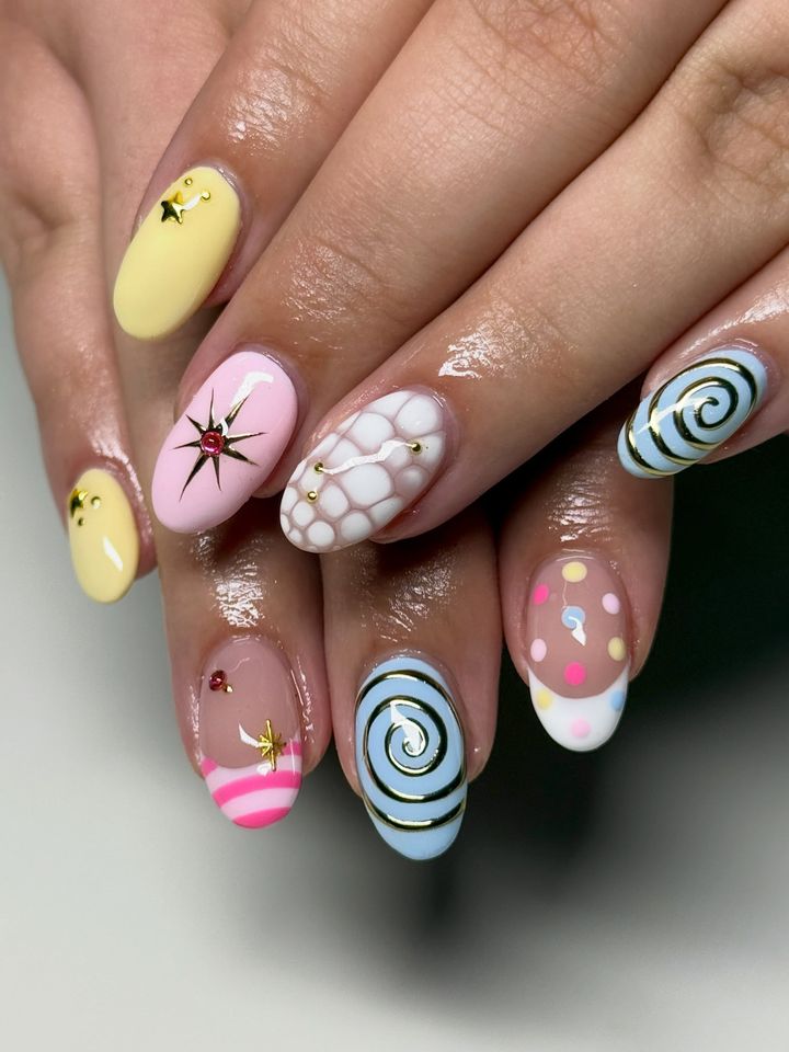 Closeup of hands with colorful and detailed nail art featuring various designs on each nail