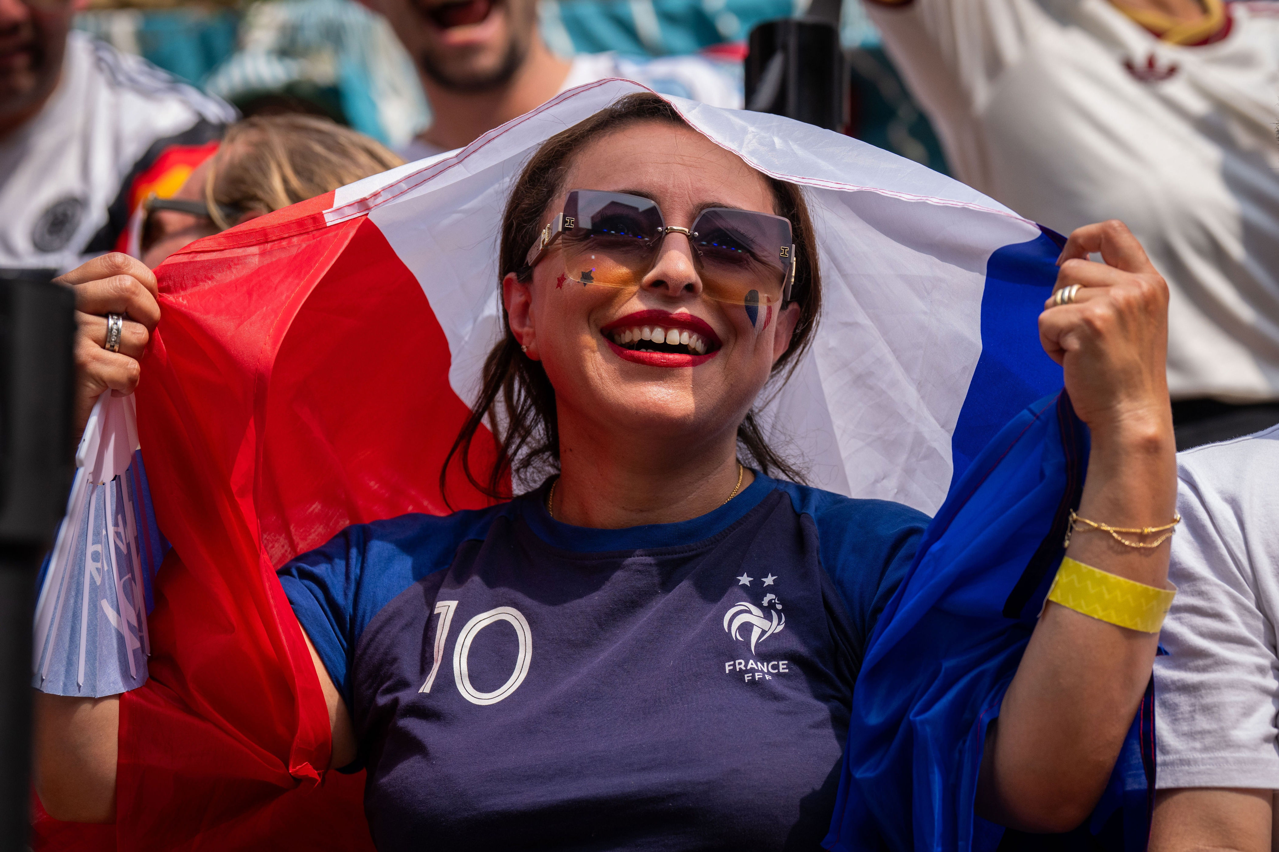 A French fan shields themselves from the sun during the World Cup semifinal soccer match between Spain and France at a watch party at the Rockefeller Center fan village, Tuesday, July 14, 2026 (AP Photo/Adam Gray)