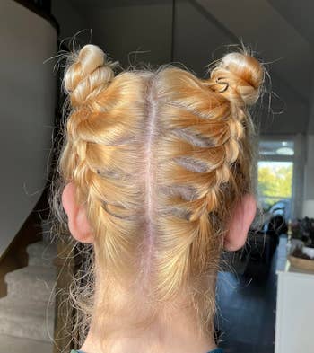 Hairstyle with two braided space buns viewed from the back, popular in casual and fashion-forward settings