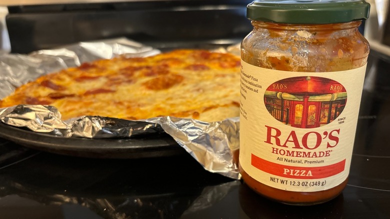Rao's homemade pizza sauce jar on stove in front of homemade pizza