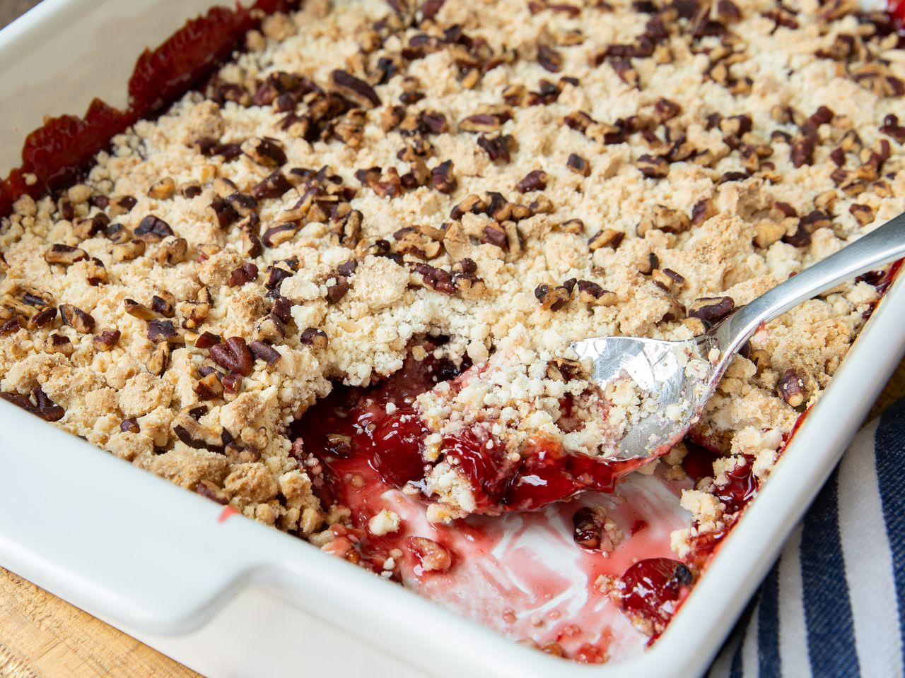 A cherry dump cake with a spoon serving a portion from a baking dish