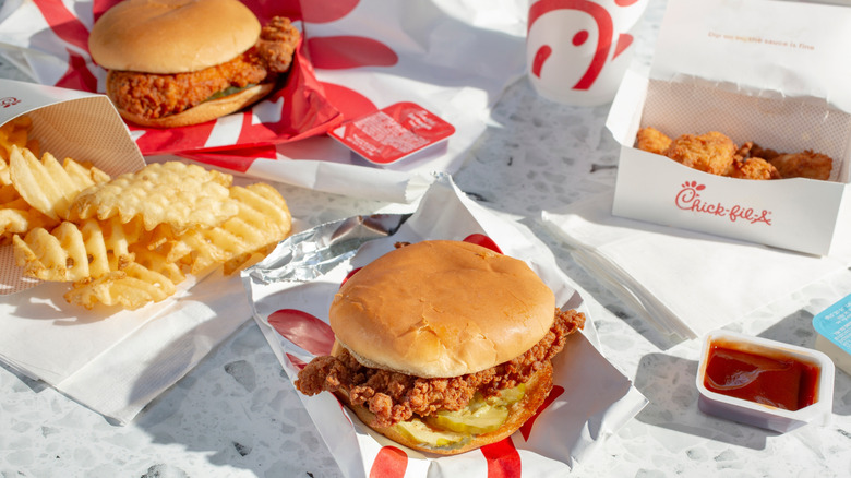Chick-fil-A chicken sandwiches pictured next to waffle fries, nuggets, and sauce