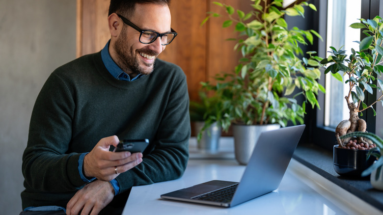 A man sitting at a table, smiling at his laptop