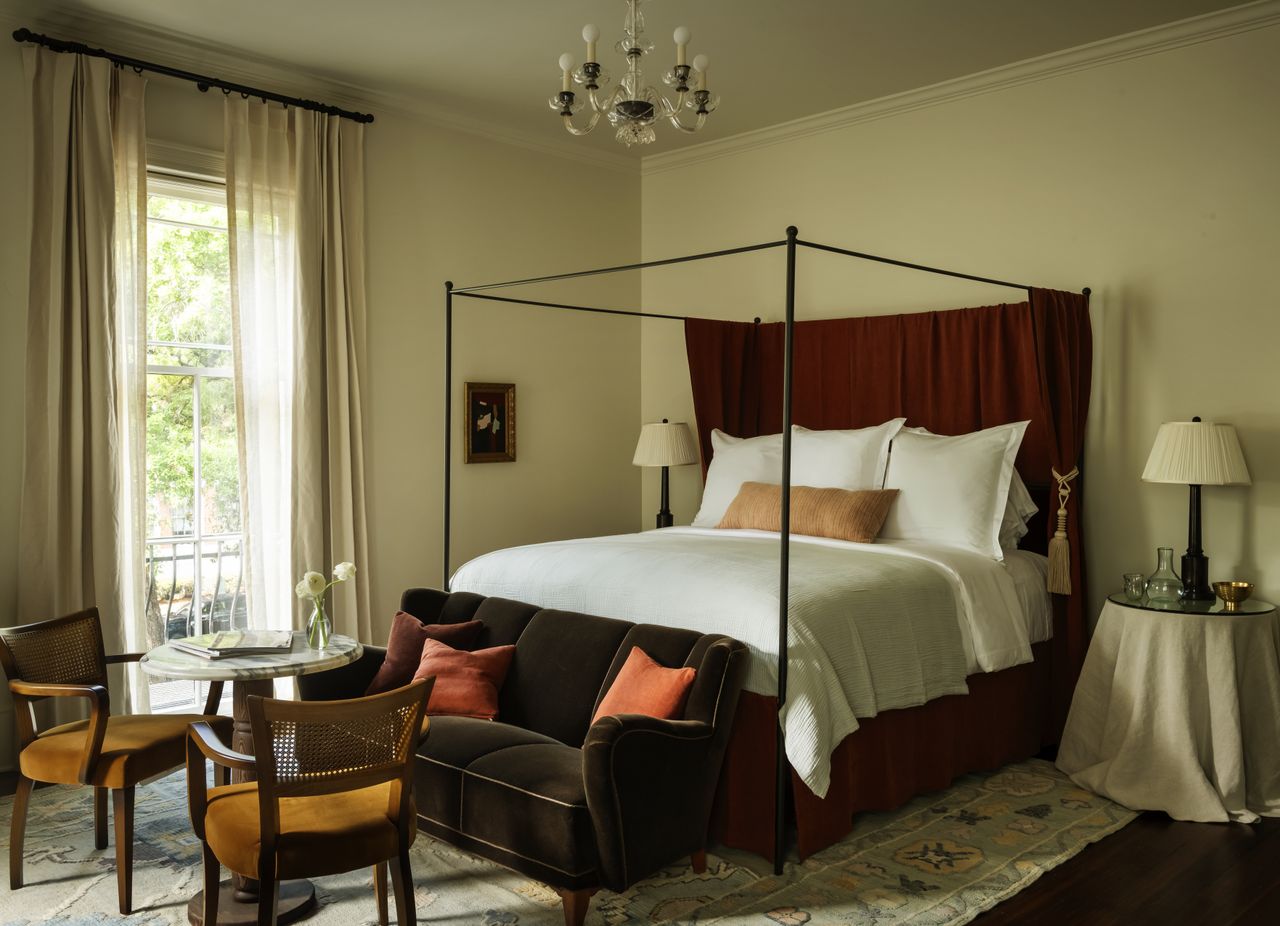 A bedroom with a canopy bed seating area and elegant decor