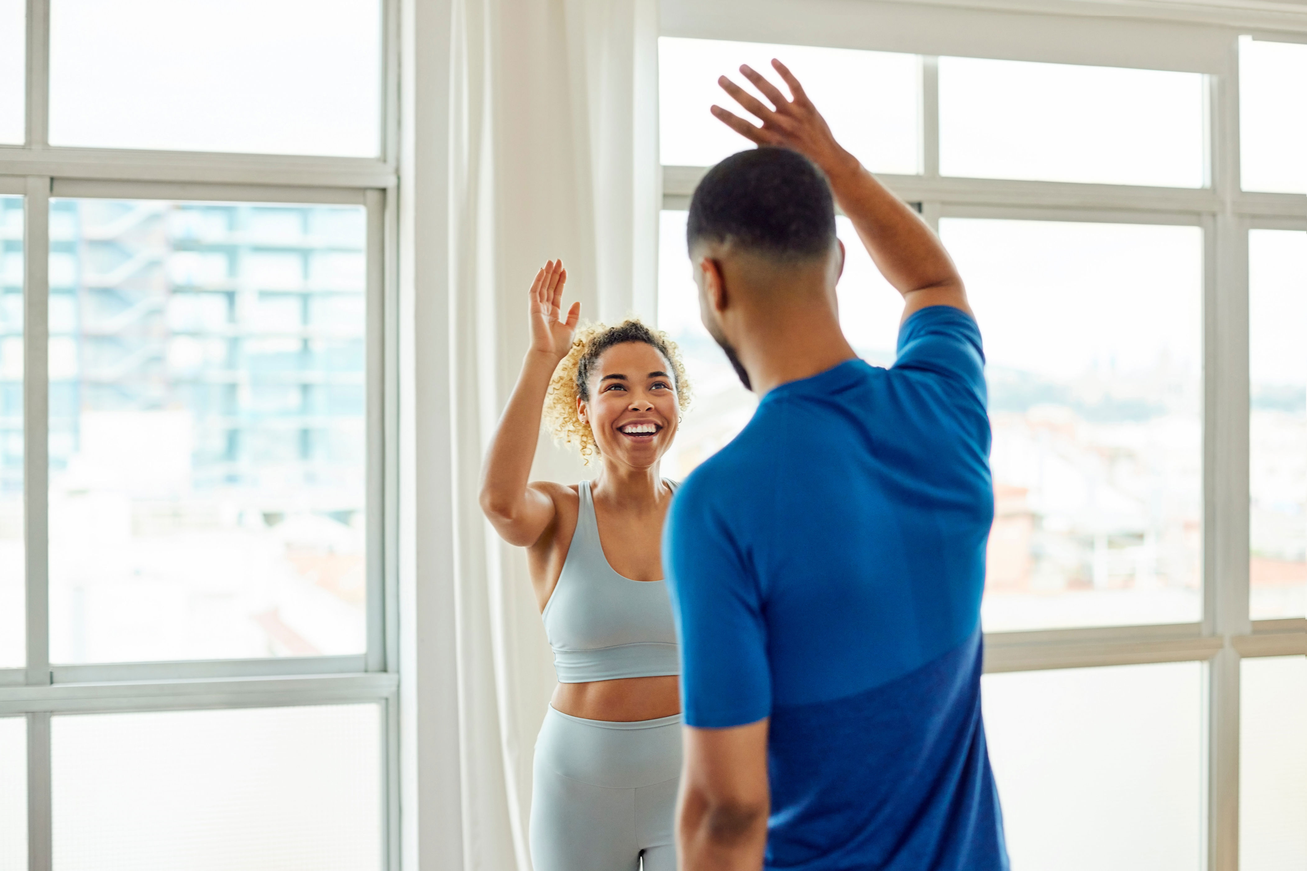 A person in activewear jubilantly gives a high five to another person indoors, conveying a sense of accomplishment and teamwork