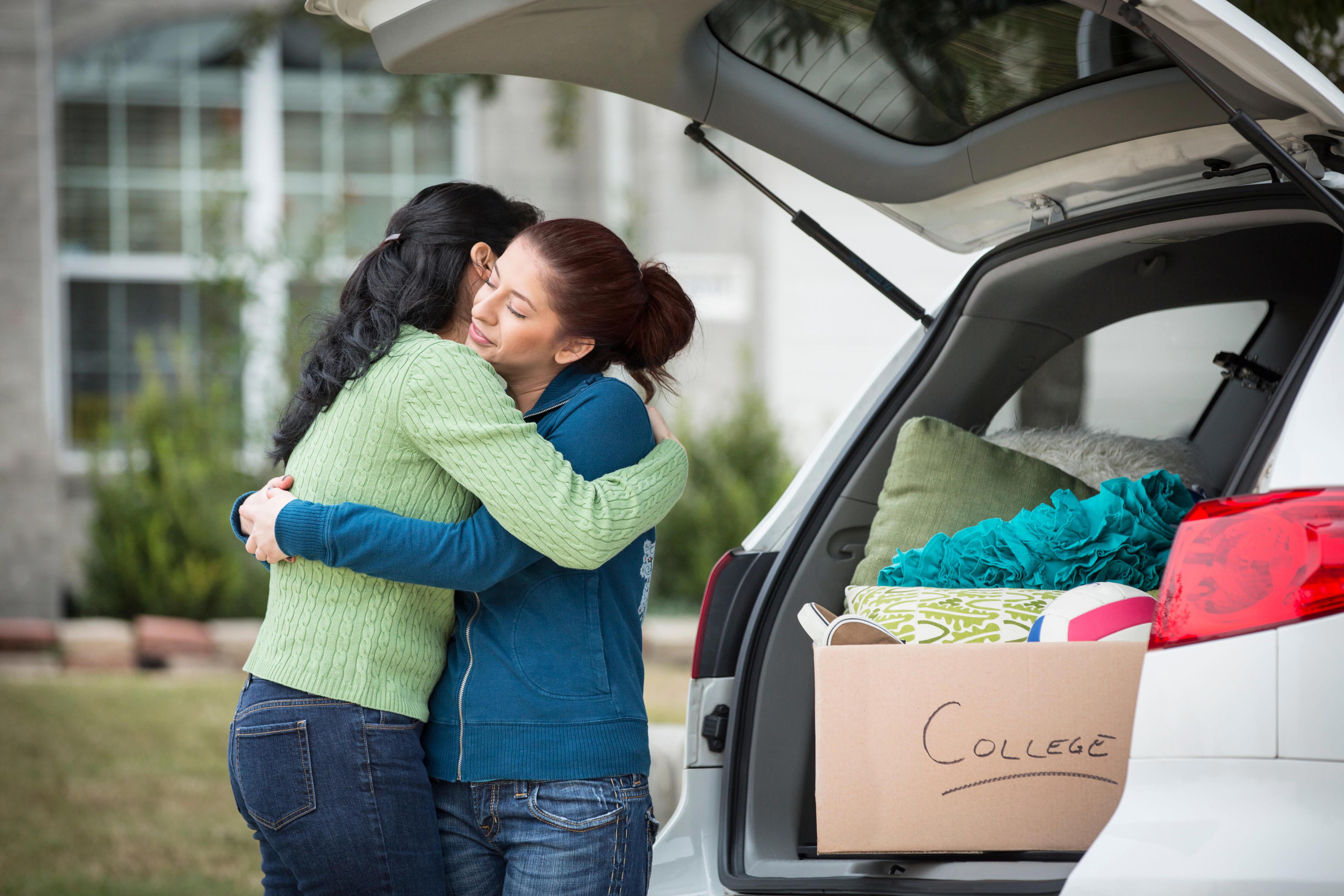 A mother hugs a daughter during college dropoff.