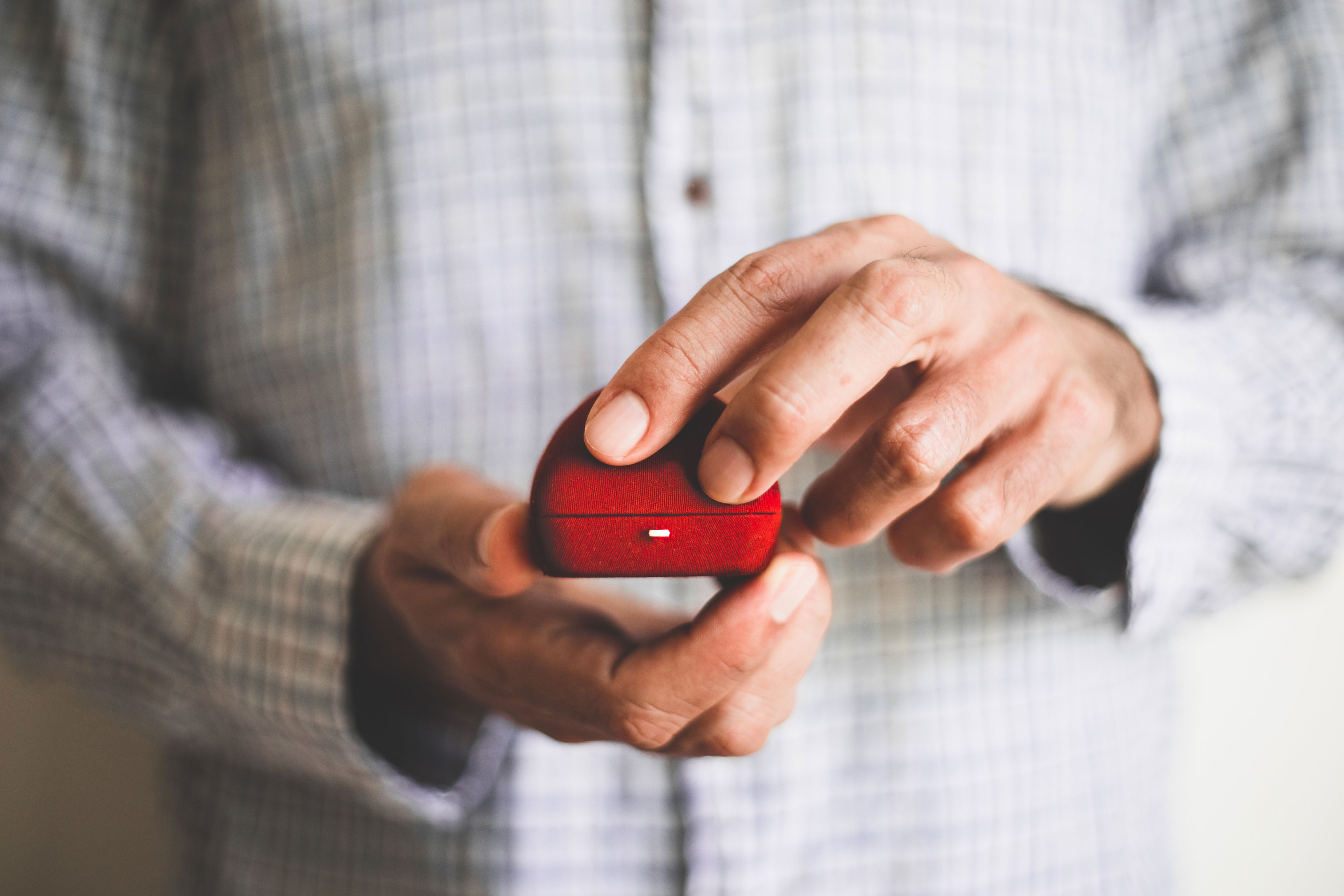 Hands opening a small red jewelry box, suggestive of a proposal or gift