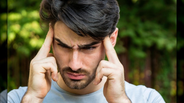 Person outside holding their ears from noise