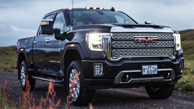 A black 2023 GMC Sierra Denali driving on a gravel road in the country.