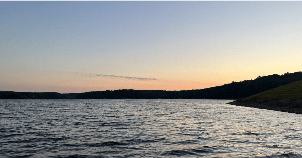 Sunset colors over the water at Deam Lake, Indiana with a dark forested horizon.