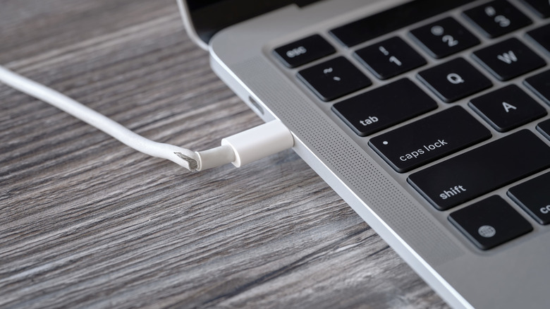 Macbook laptop plugged into frayed damaged cable