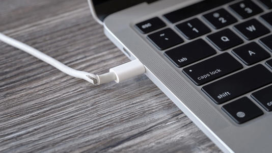 Macbook laptop plugged into frayed damaged cable