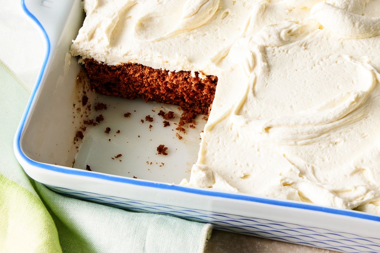 A mahogany cake with a portion removed displayed in a rectangular dish and topped with frosting