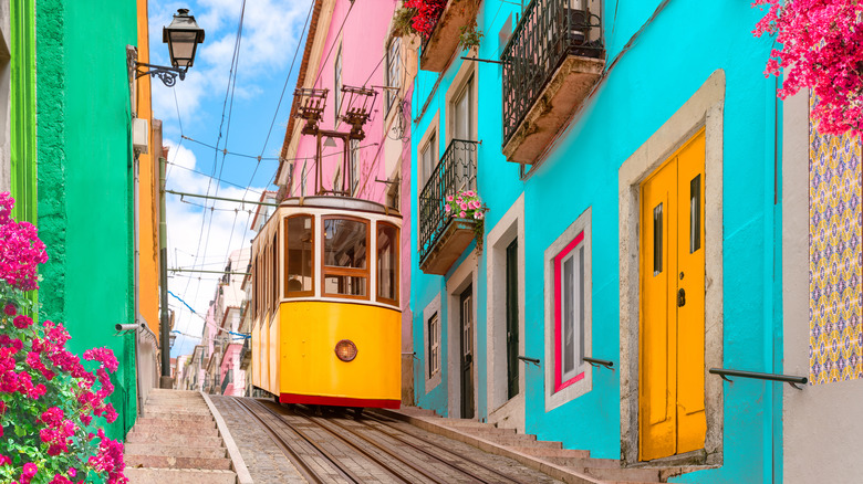 A vibrant yellow tram traversing the rails among colorful buildings in Lisbon, Portugal