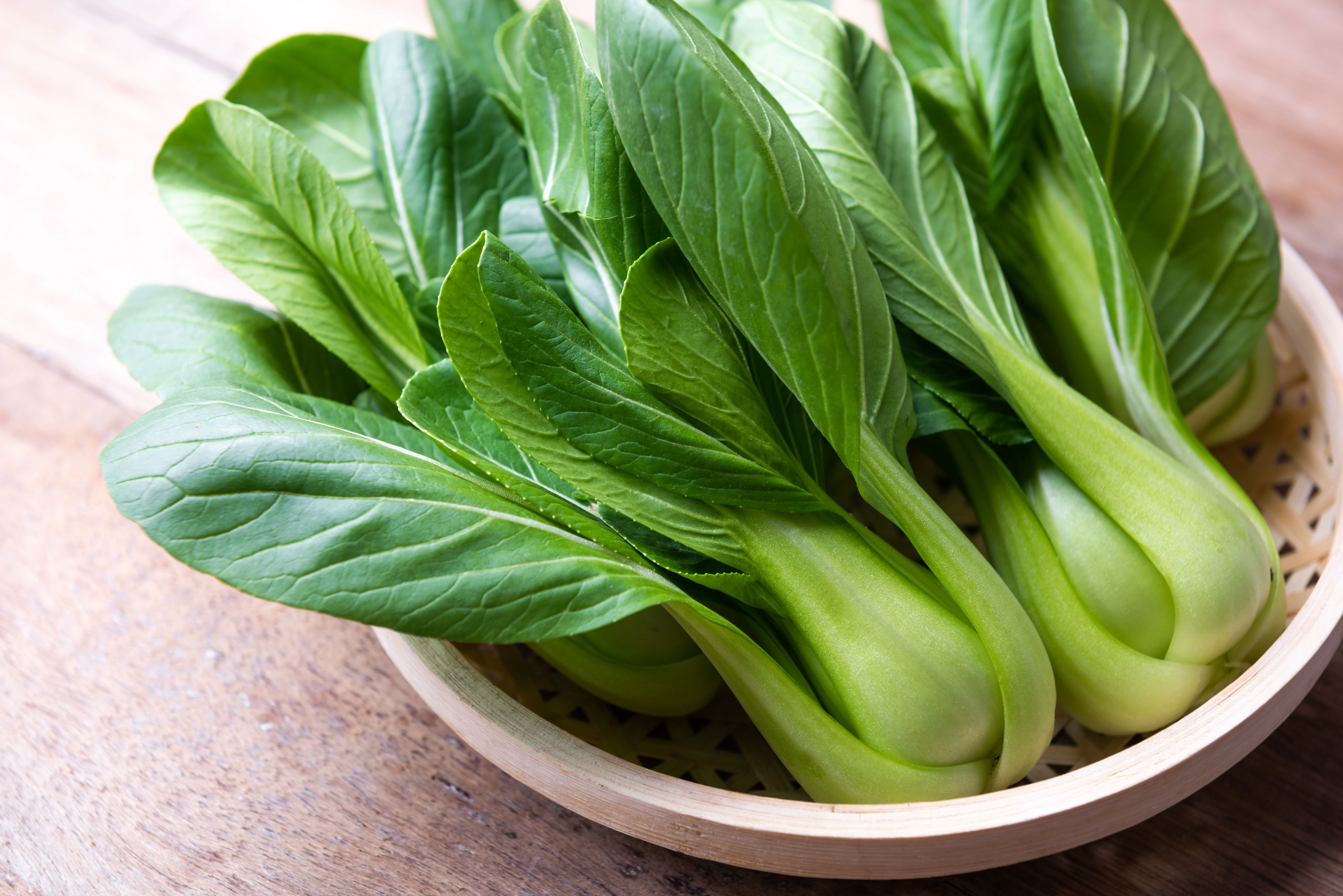 Fresh bok choy arranged in a wooden basket on a table