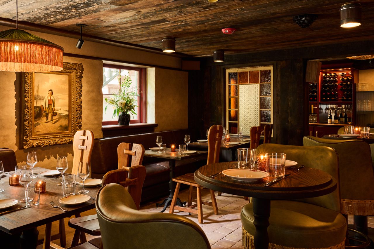 A cozy wellfurnished restaurant interior with wooden tables and chairs dim lighting and a framed painting on the wall