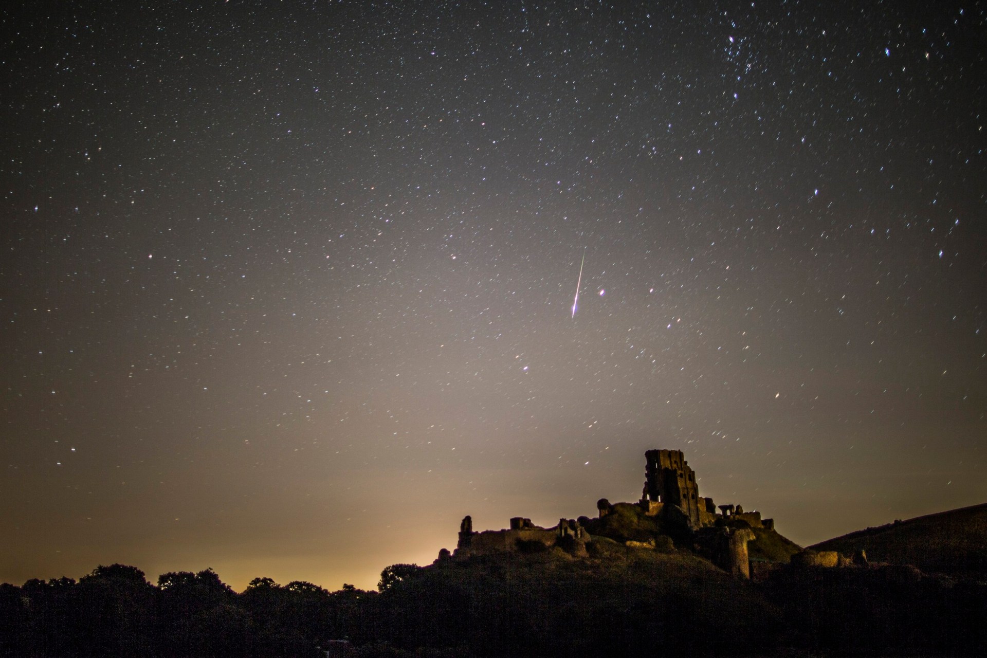 A Perseid Meteor flashes across the night sky above Corfe Castle on August 12, 2016 in Corfe Castle, United Kingdom.
