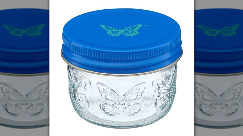 Small blue jar with butterfly design and a blue lid with a teal butterfly on it