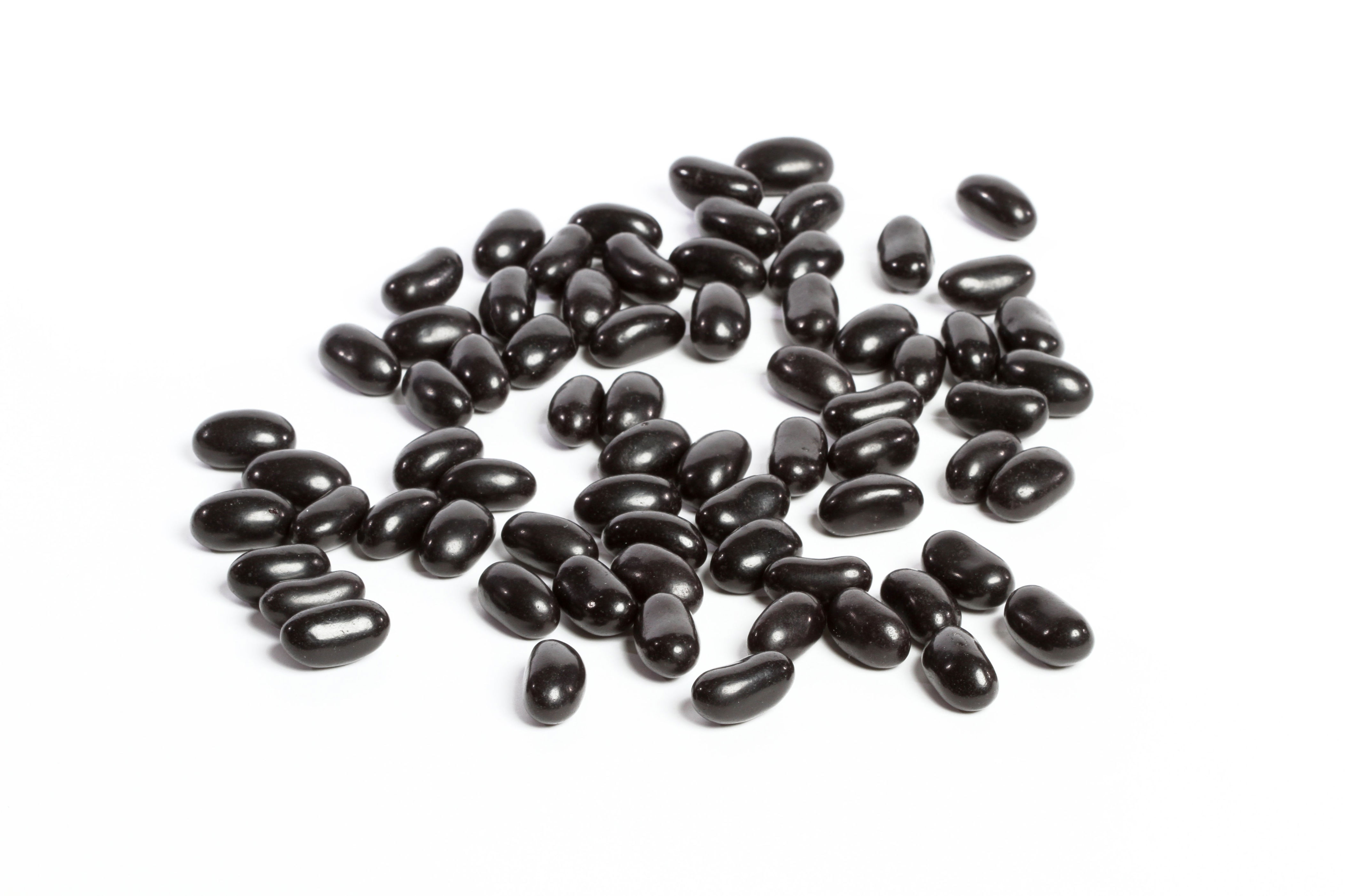 Black jelly beans scattered on a white background