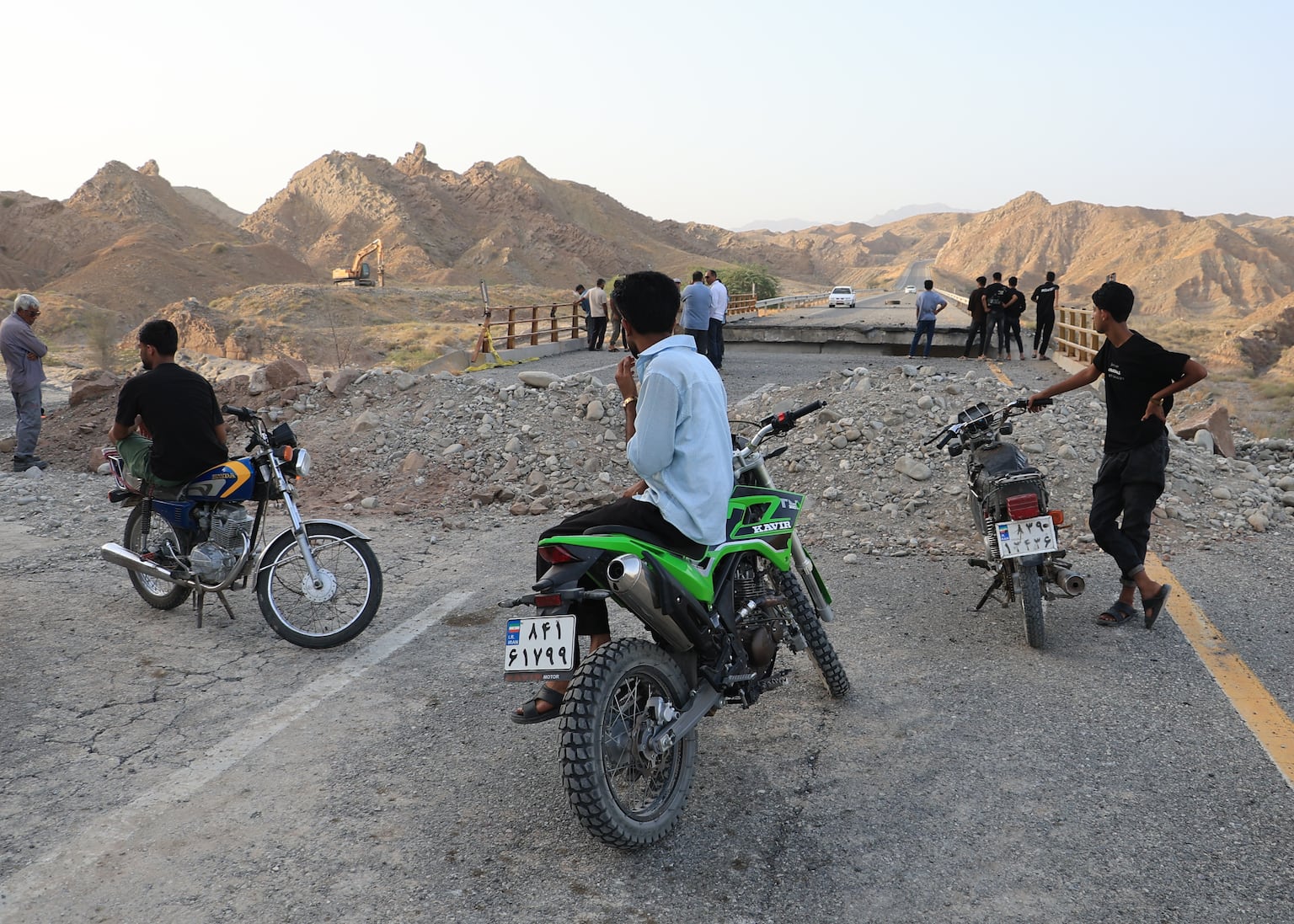 People stand on a bridge destroyed after a strike in Hormozgan province, southern Iran (Amirhosein Khorgooi/Iranian Students’ News Agency/AP)