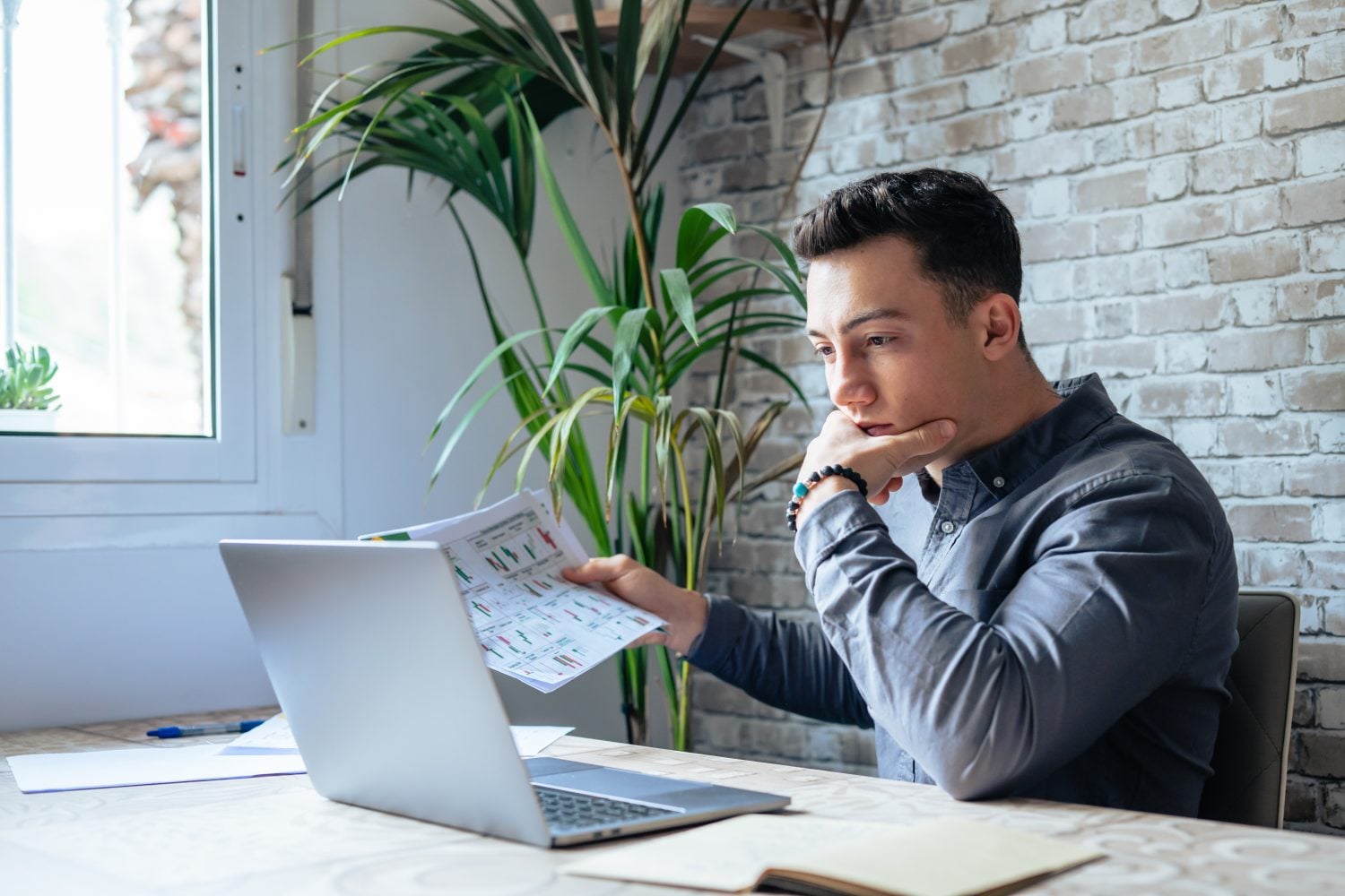 Caucasian business man trader investor analyst looking at financial stock market charts rate dynamic, trading data indexes growth using mobile phone and laptop for cryptocurrency digital analytics.