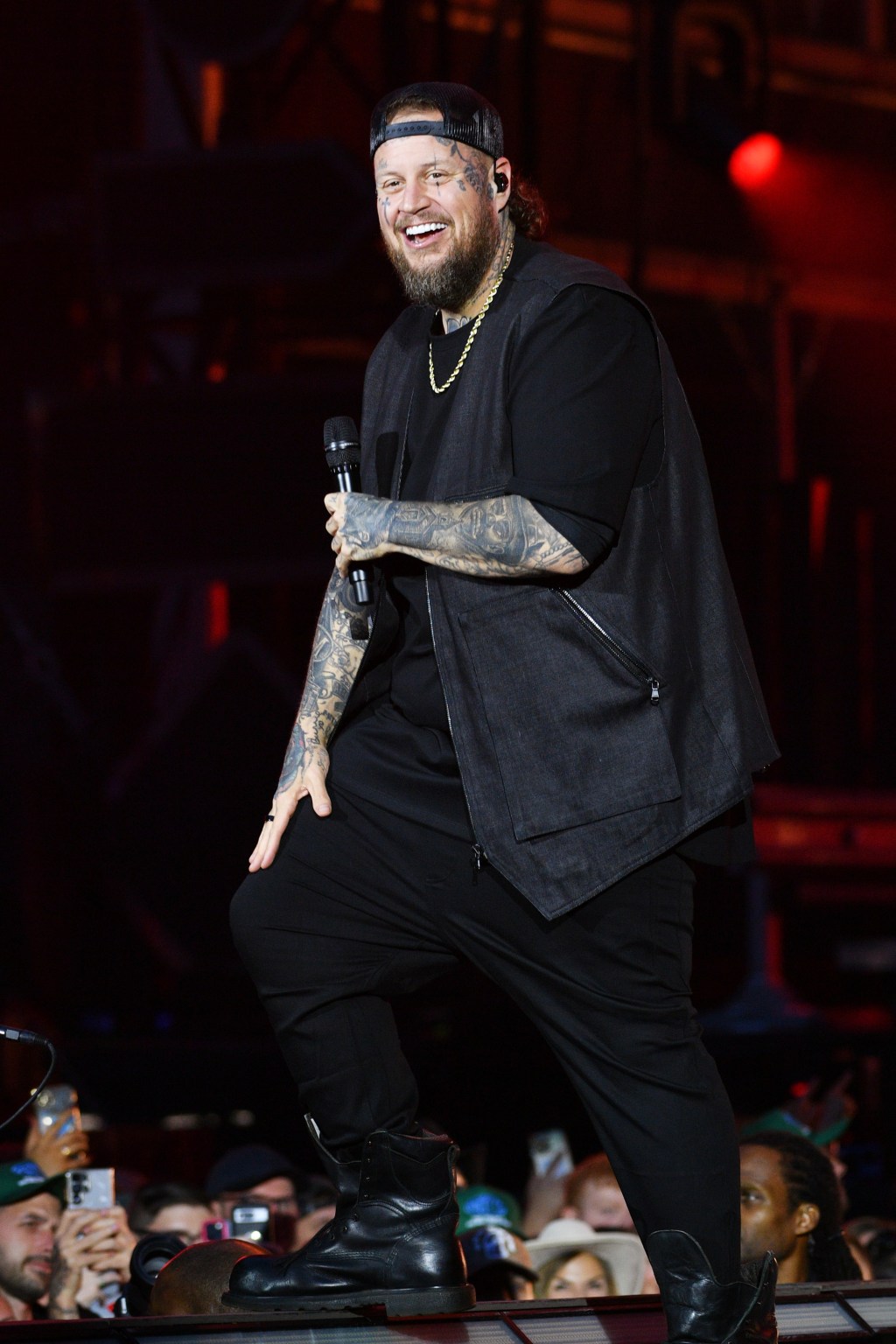 Jelly Roll performing on stage, wearing a black outfit and holding a microphone.