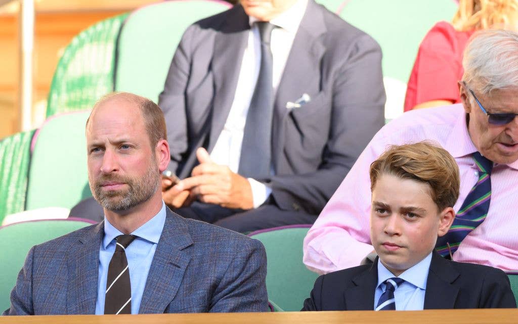 Prince William, Duke of Cambridge, and Prince George of Cambridge sit in stadium seats, both in suits and ties.